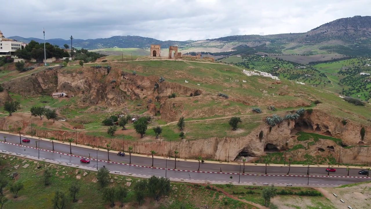 Vista aerea con drone di storiche mura fortificate che circondano verdi colline e paesaggi a Fez, Marocco, ideale per viaggi culturali e progetti documentaristici