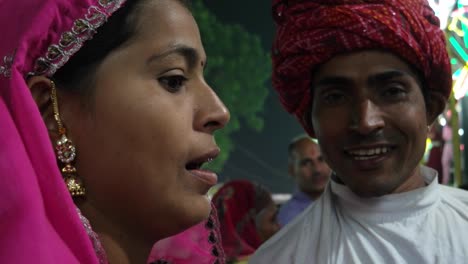 indian traditional couple talking in pink sari and red turban at pushkar mela, a carnival of rajasthan, india