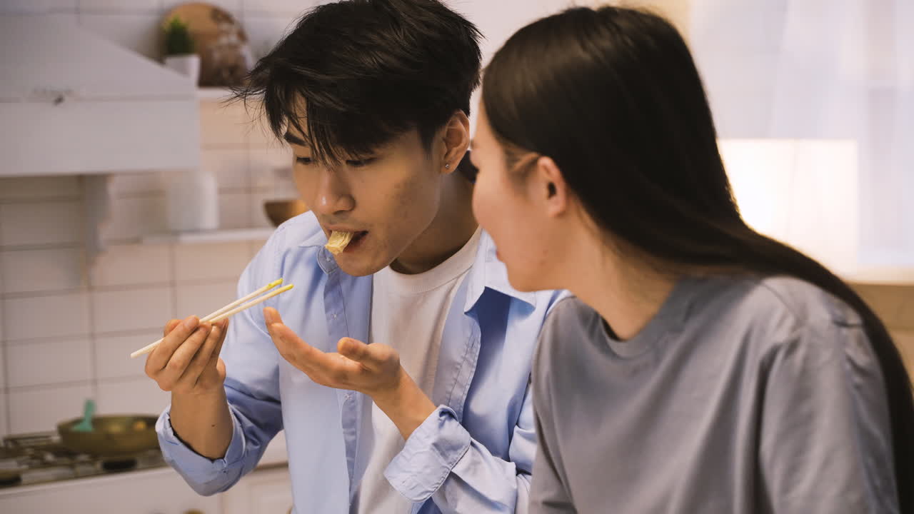 부엌 카운터 주위에 앉아 일본 음식을 먹는 일본 친구들의 클로즈업 보기 1