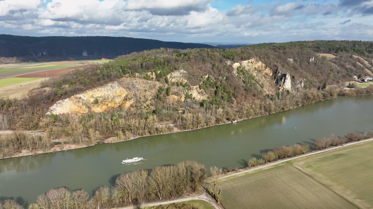 Soaring above a beautiful river in Germany. This footage showcases the harmony between nature and industry, with boats traveling through a tranquil landscape