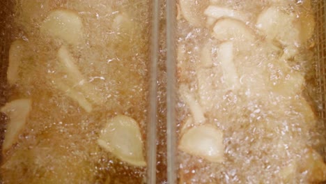 primer plano de trozos de patata fritos en cestas en aceite, movimiento vertical