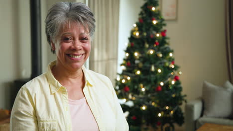 smiling senior woman enjoying christmas at home with decorated tree