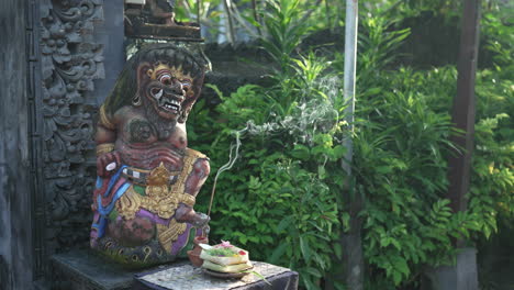 balinese guardian statue with incense offerings at a temple