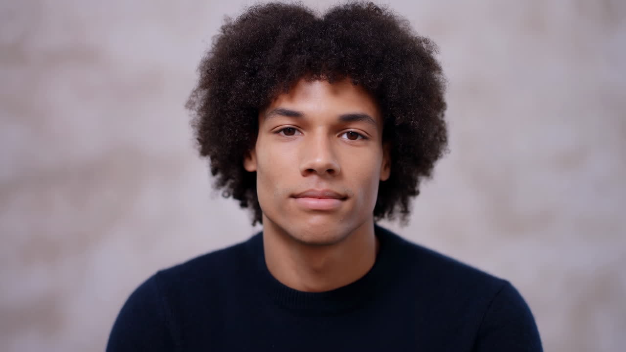 Portrett av en ung mann med afrohår som ser inn i kameraet.