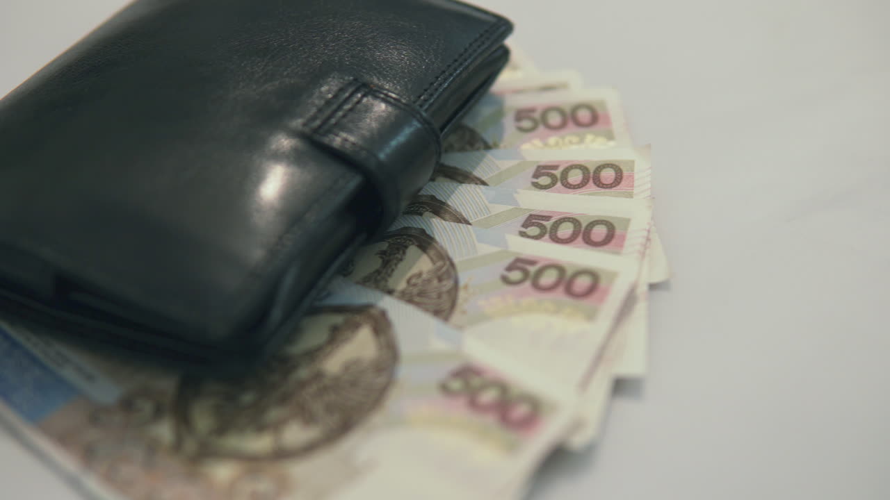 Deslizando: da esquerda para a direita, 500 zloty polacos debaixo de uma carteira preta.