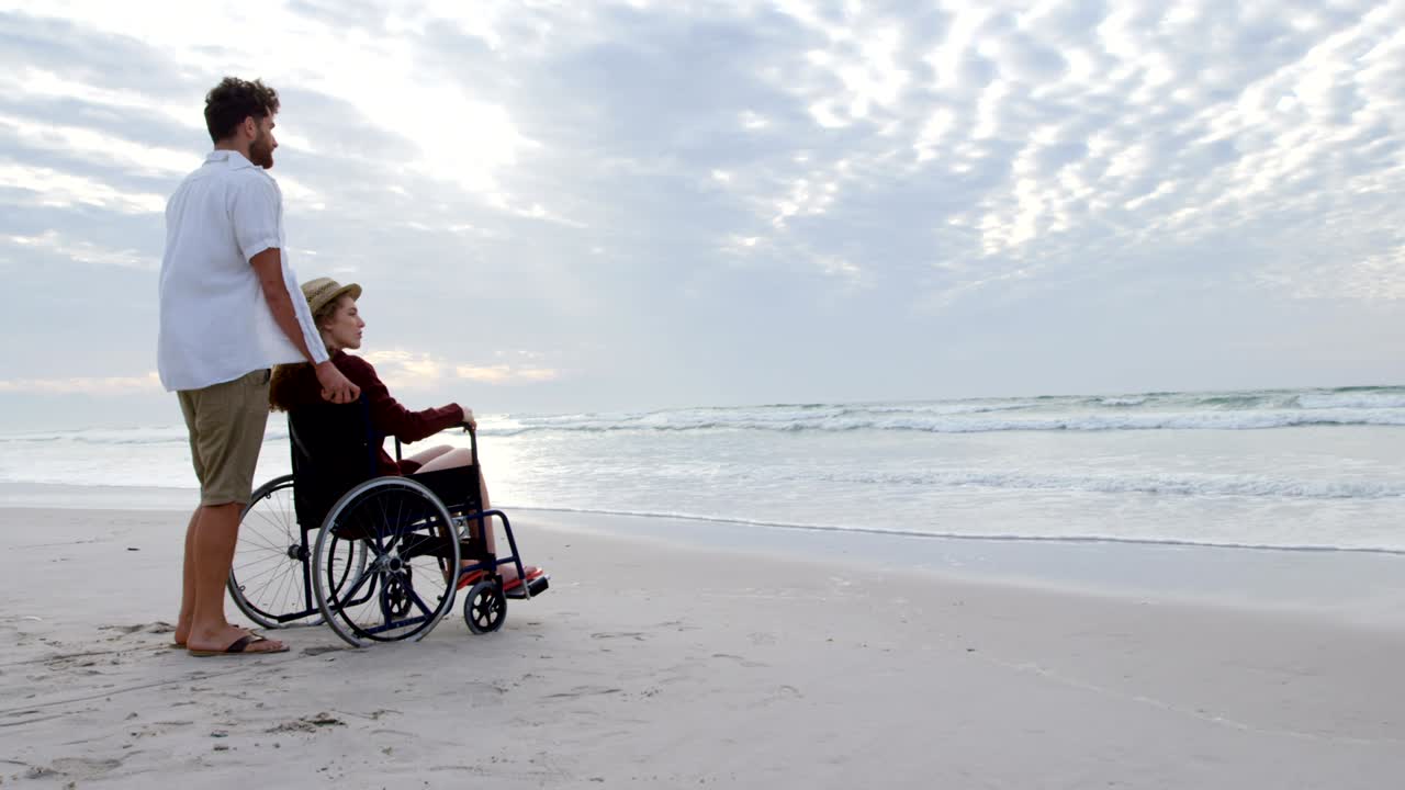 Side view of young caucasian couple looking at sea on the beach 4k