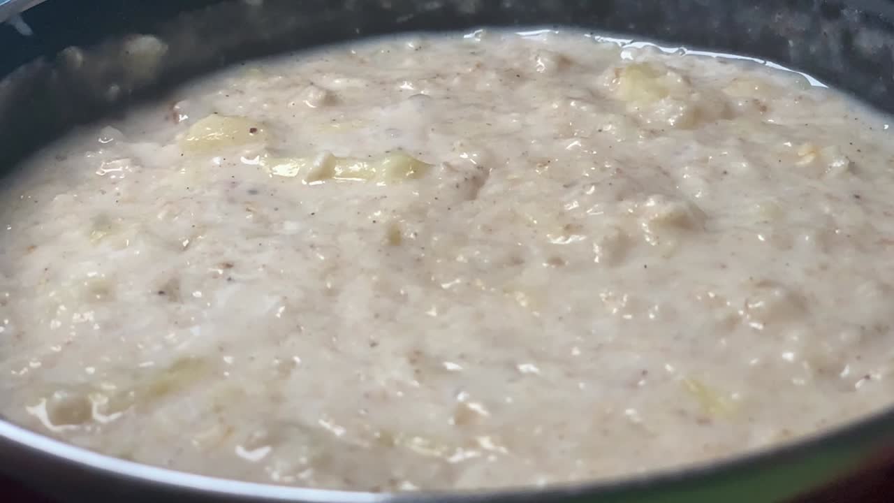 Memasak bubur oatmeal di panci hitam dalam gerak lambat