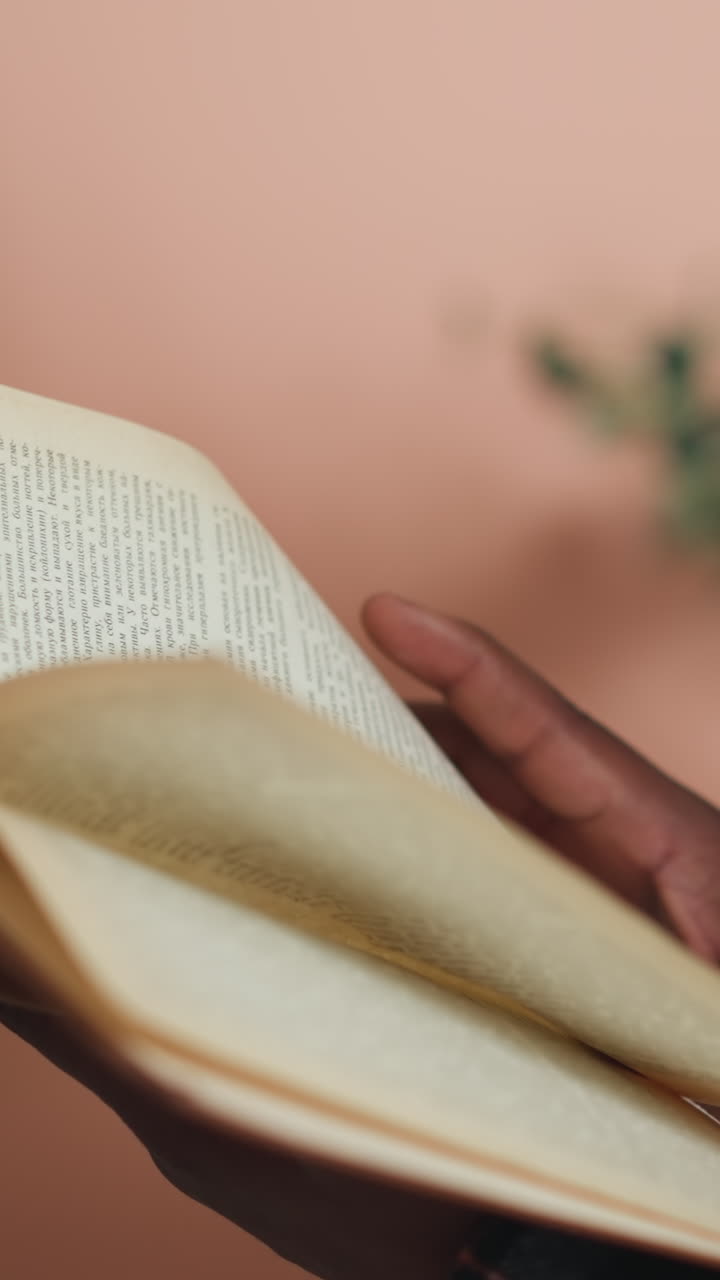 hombre da la vuelta a la página de un libro en la biblioteca de la universidad. estudiante negro absorto en la lectura de literatura en el centro de información preparándose para exámenes. cliente en la librería