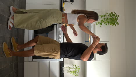 disparo vertical de un hombre latino mexicano en forma sorprendiendo a su esposa novia mientras ella está cocinando en la cocina y comenzar a bailar con ella