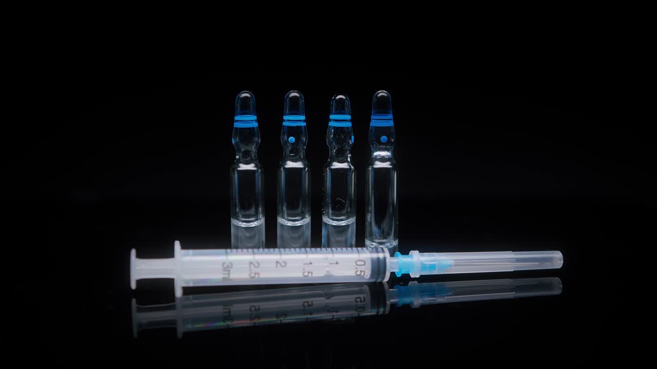 close-up de jeringas y ampollas con vacuna contra el coronavirus. mostrando muestra de medicamento en fondo negro, vacunación contra covid-19, concepto de investigación de laboratorio