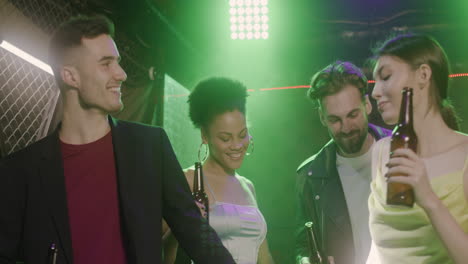 group of four young friends holding beer and dancing at disco 2