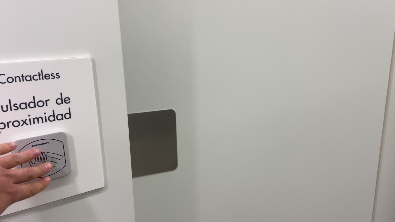 primer plano de una persona que presiona un botón de proximidad sin contacto que abre una puerta