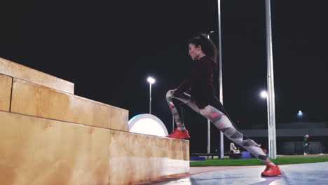 sportliches, lockiges mädchen, das nachts auf der treppe im park ausfallschritte macht 1