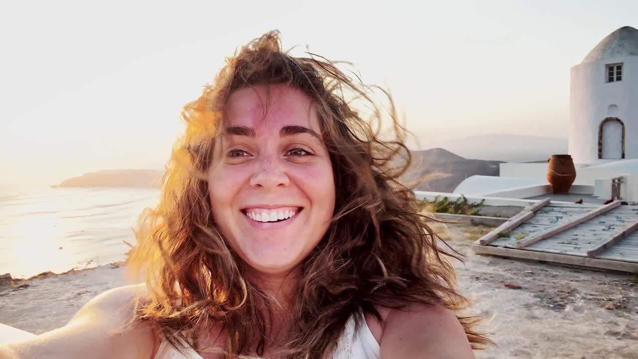 Giovane donna che si gode il tramonto a Santorini con i capelli al vento