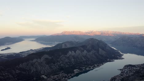 Vista-Aérea-De-Aguas-Tranquilas-De-La-Bahía-Sinuosa-Interrumpida-Por-Enormes-Acantilados-Y-Montañas-Durante-La-Hora-Dorada