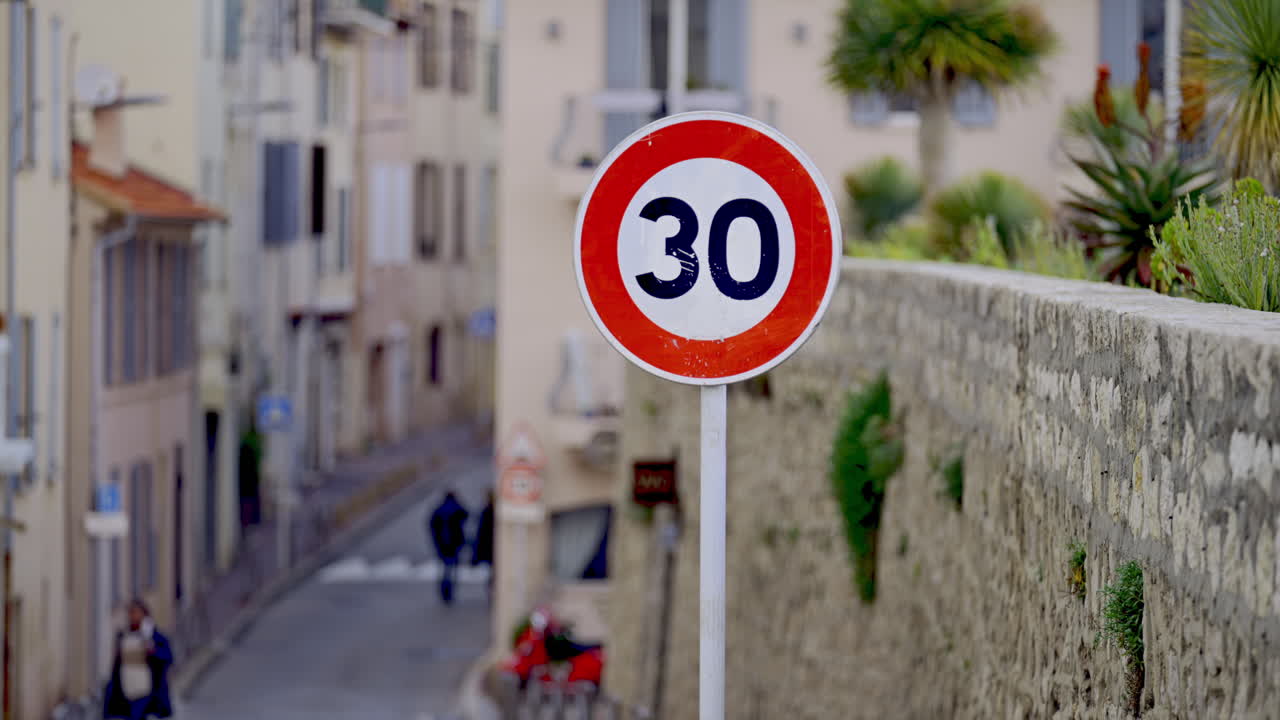 People walking on the streets of the city in daylight in Antibes, 30 road sign