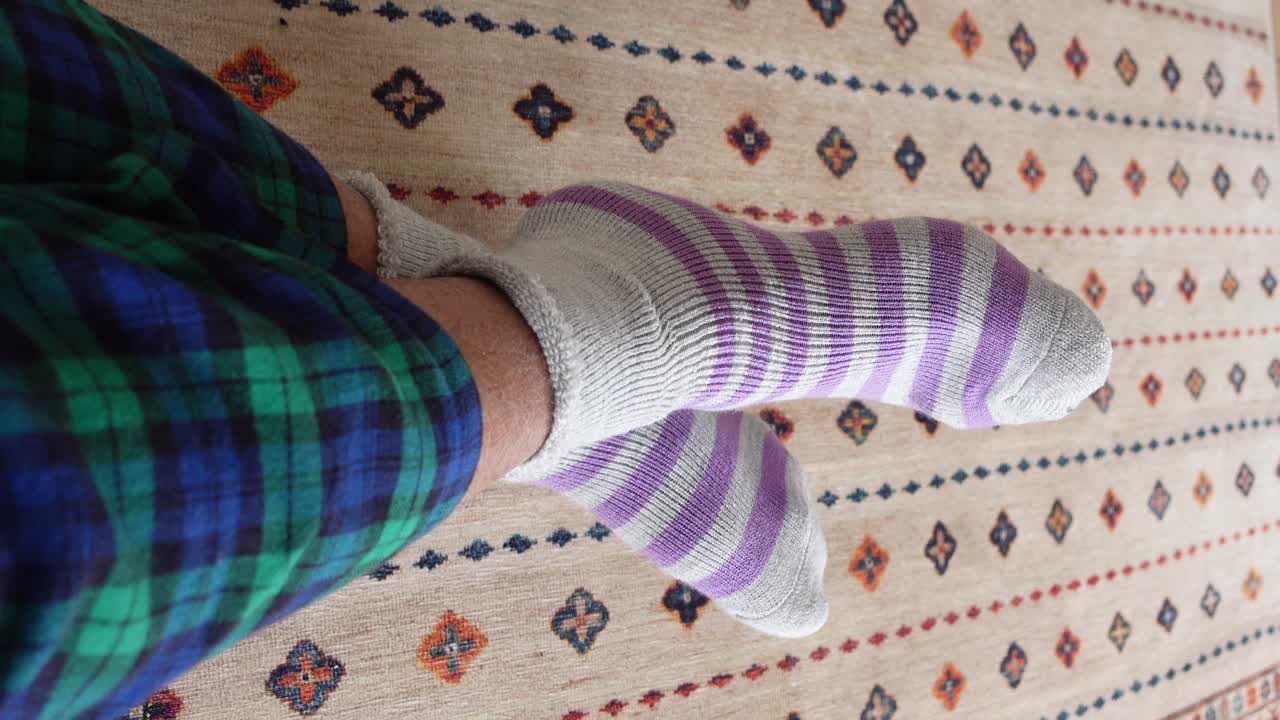Person Wearing Striped Socks and Plaid Pajamas on a Carpet