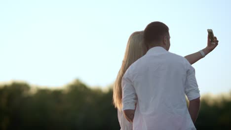 Romantic-couple-taking-photo-at-sunset.-Sweet-moment-for-lovely-couple