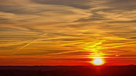 a beautiful orange sunrise under a cumulus cloud cover over a plain