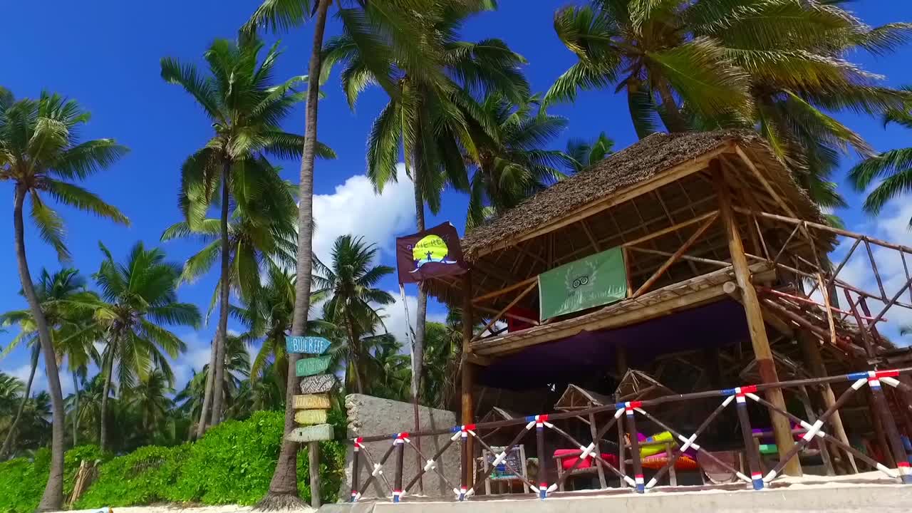 foto de una palapa y palmeras de coco y la bandera ondeando en la playa de jambiani zanzíbar