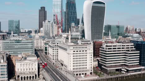 rising drone shot from red buses on london bridge revealing city skyscrapers