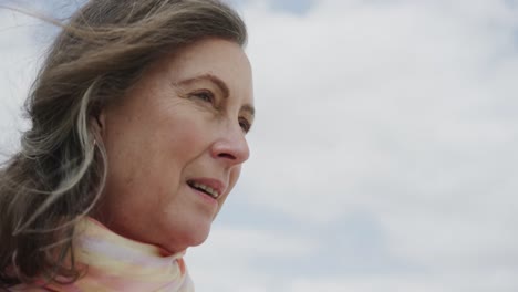 Happy-senior-caucasian-woman-smiling-against-cloudy-sky,-in-slow-motion