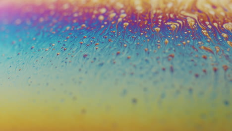 rainbow colored surface with a lot of small drops rising to the top