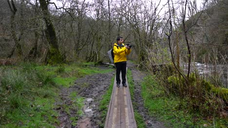 el fotógrafo camina por un sendero de madera en el parque nacional brecon beacons, deteniéndose para tomar fotos.