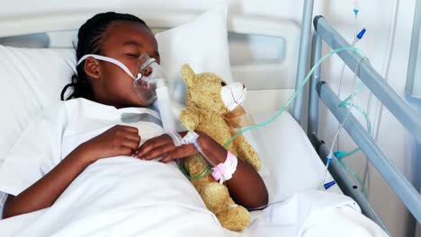 sick girl in oxygen mask resting with teddy bear