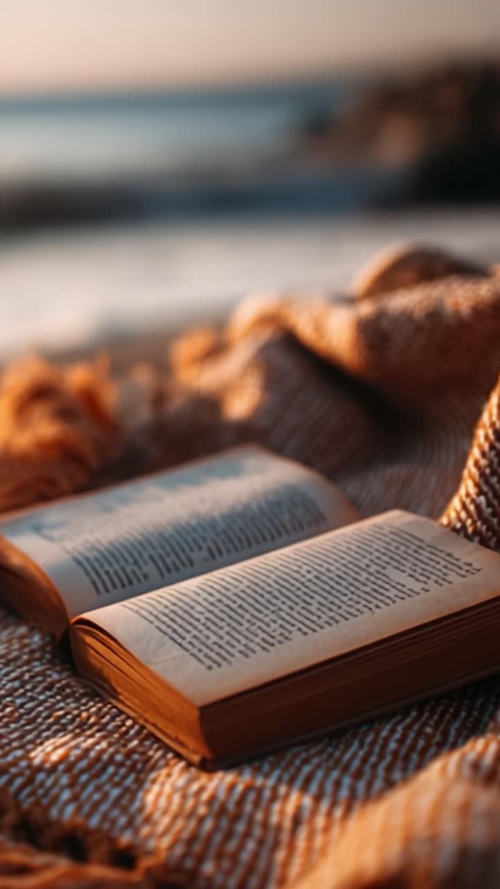 Een sereen moment vastgelegd: twee open boeken rustend op een knusse deken aan de kust, badend in zacht gouden licht, wat een gevoel van rust en reflectie oproept
