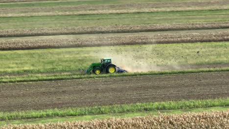 flock of birds flying around driving tractor on farm field during sunny day