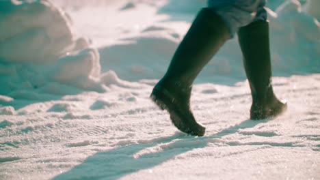 close-up view of a person walking on snow on a sunny day, lot of footprints on the pathway