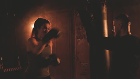 woman boxer knocks repeatedly on her trainer's gloves