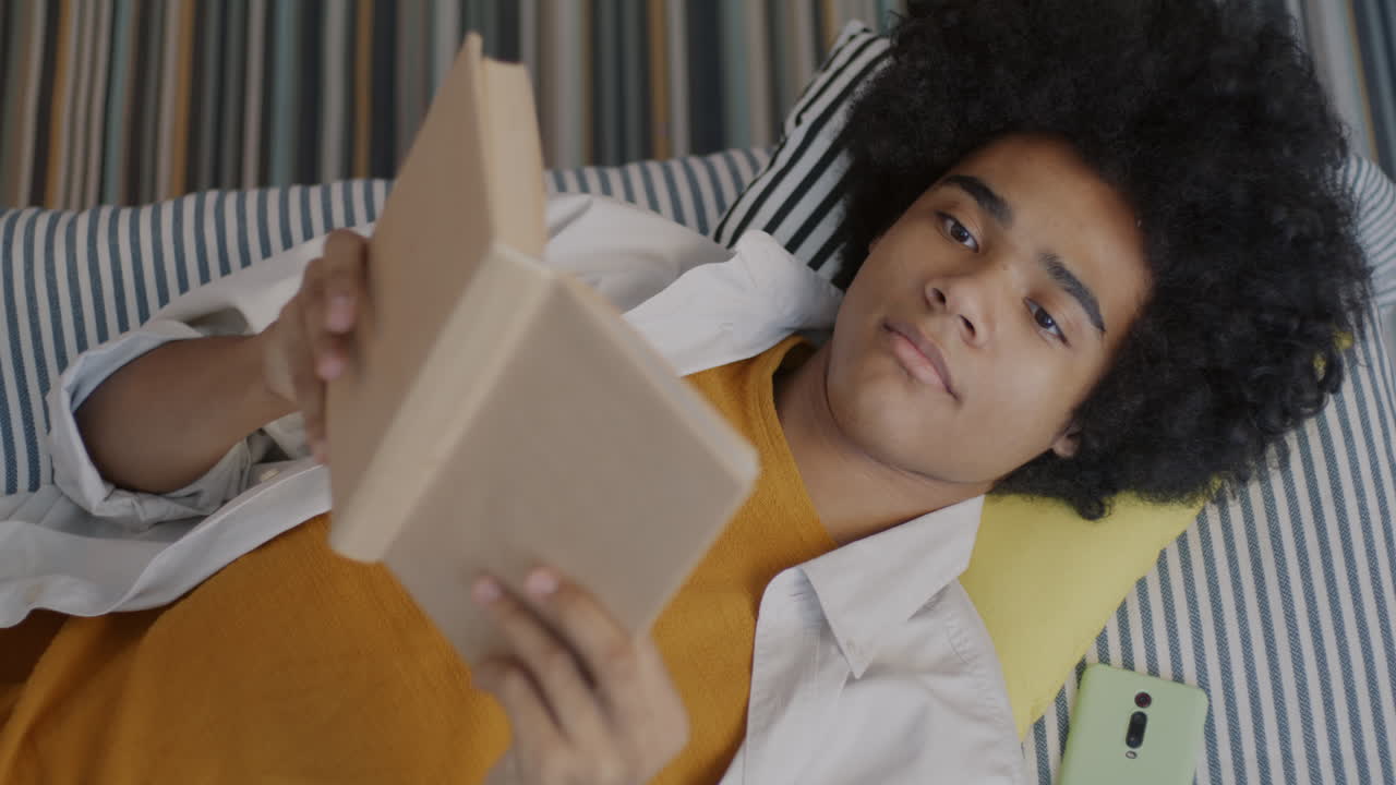 Junge Person liest ein Buch auf einem Sofa