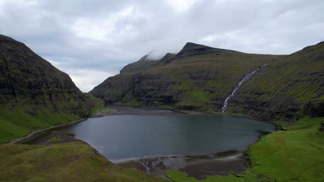 dramatic view of saksun village and its lagoon with a traditional turf-top house, aerial