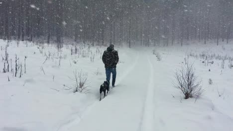 a man with a camouflage jacket walks on a snowy path during a snowstorm