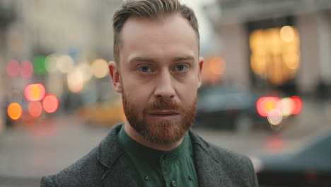 retrato de feliz hombre de negocios caucásico con barba sonriendo alegremente a la cámara en la calle en otoño