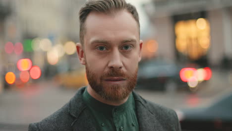 portret van een gelukkige blanke zakenman met een baard die in de herfst vrolijk naar de camera glimlacht op straat