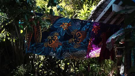 traditionally dyed and printed tropical sarong with vivid turtle and flower theme on a line blowing in the wind