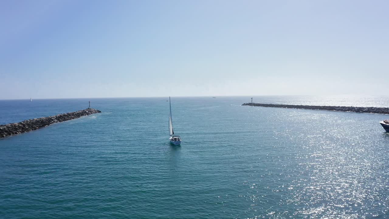 방파제 사이 베이 채널에서 항해하는 범선, 태양 광선은 바다 표면에 반사