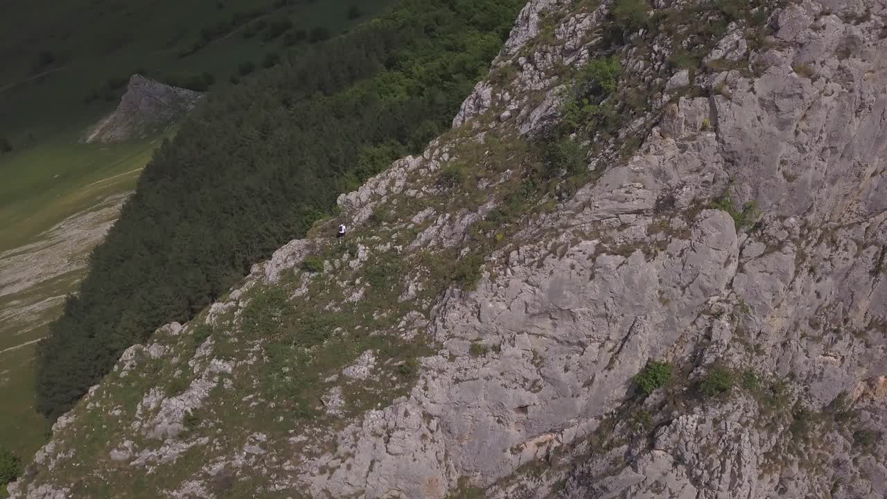 Drone Footage Of Mountain Climber, Climbing Towards The Summit Of Rocky Steep Escarpment