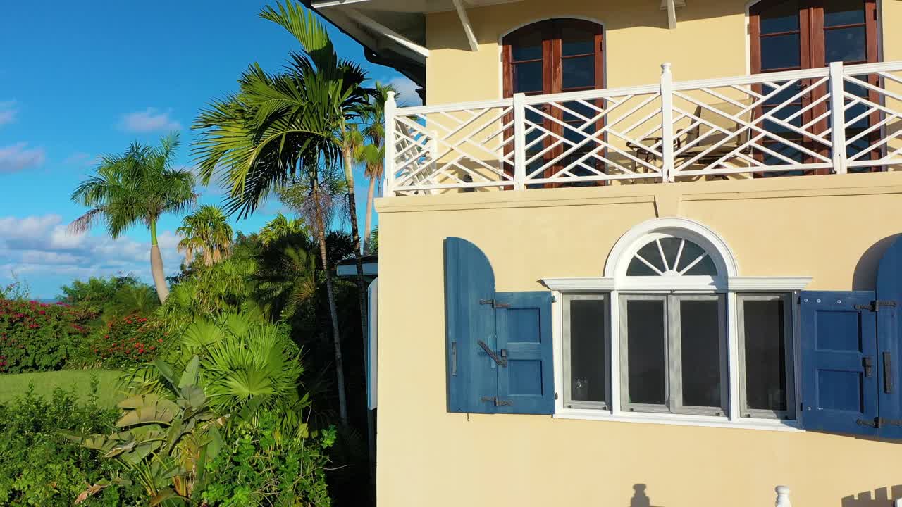High-end vacation retreats are hidden in the trees along a Caribbean coastline in St. Croix, USVI, captured in this sunny midday aerial view with shimmering blue water and vibrant skies