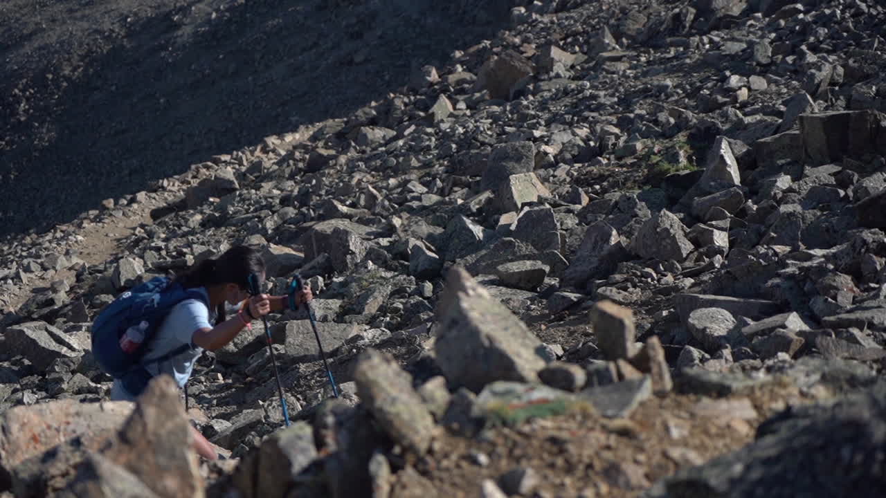 화창한 날 슬로우 모션으로 바위 언덕에 트레킹 기둥을 가진 산악인 여성