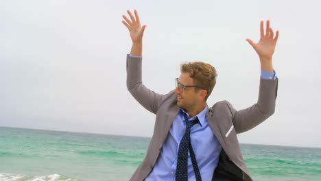 vista frontal de un hombre de negocios caucásico bailando en la playa 4k