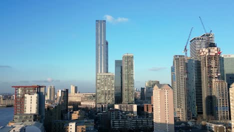 canary wharf cbd skyline against blue sky on river thames, aerial view