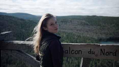 encantadora joven parada en una plataforma de observación de madera posando para una foto con el fondo del lago forestal en saint-come, quebec, canadá