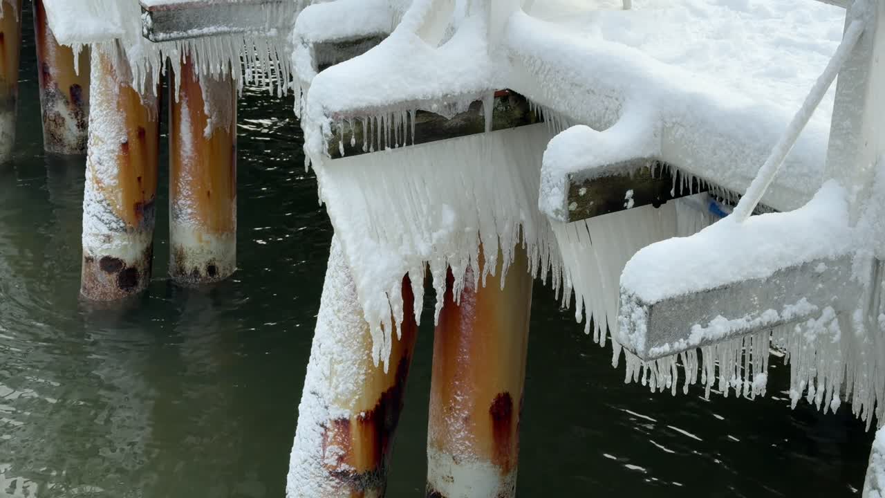 Pontile ghiacciato con ghiaccioli pendenti sul tranquillo Mar Baltico. Inverno freddo in Polonia.