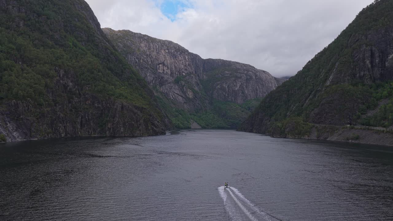 Drönarbild av fjordlandskap med snabb båt som skär genom vattnet