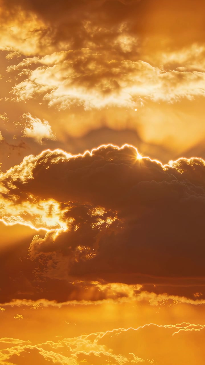 Vertikales Video: Pulsierendes Sonnenlicht lugt bei Sonnenuntergang hinter einer großen Kumuluswolke hervor und wirft Strahlen.