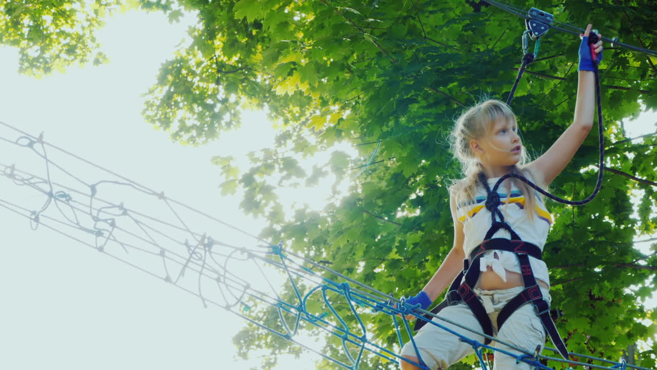 un niño valiente camina por la cuerda floja entre árboles altos infancia activa y diversión